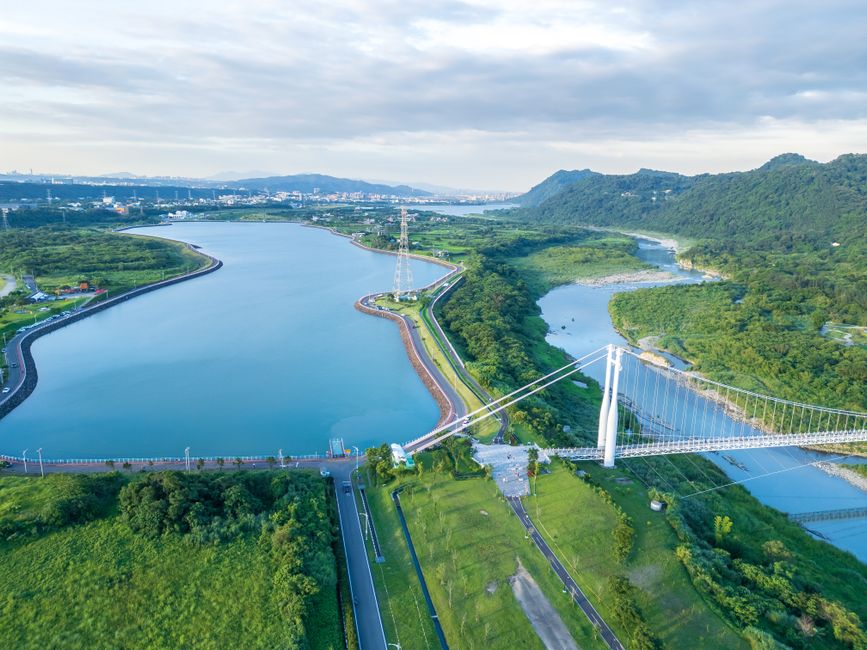 Stunning aerial shot of a picturesque river and bridge surrounded by lush greenery.