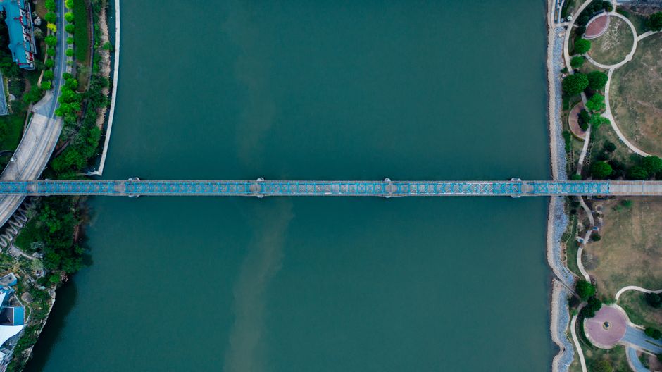 Drone view of modern bridge connecting districts of city located on shore of calm river