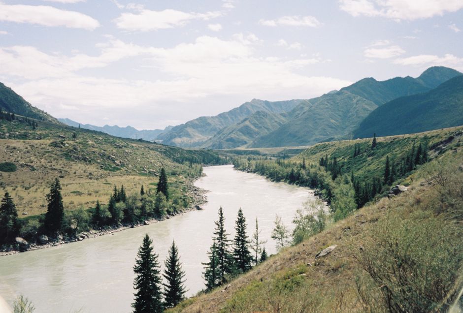 Beautiful mountain landscape with a river flowing through a lush green valley under a clear sky.