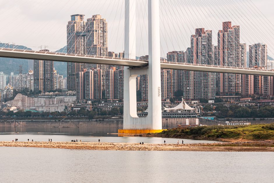 Scenic view of a modern bridge crossing a river with a skyline of high-rise buildings in the background.