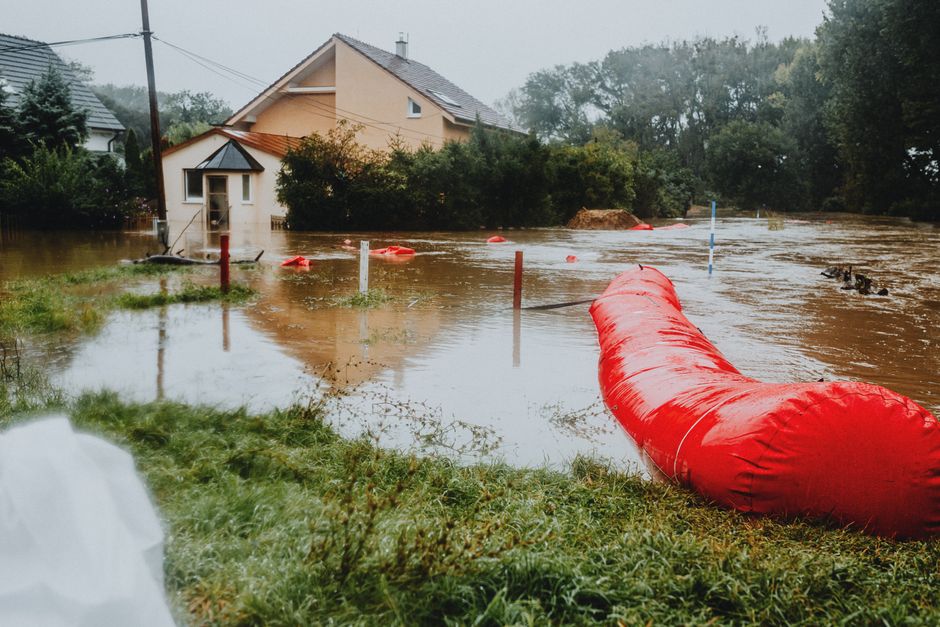 Flooded residential area protected by red flood barriers, showing severe weather impact.